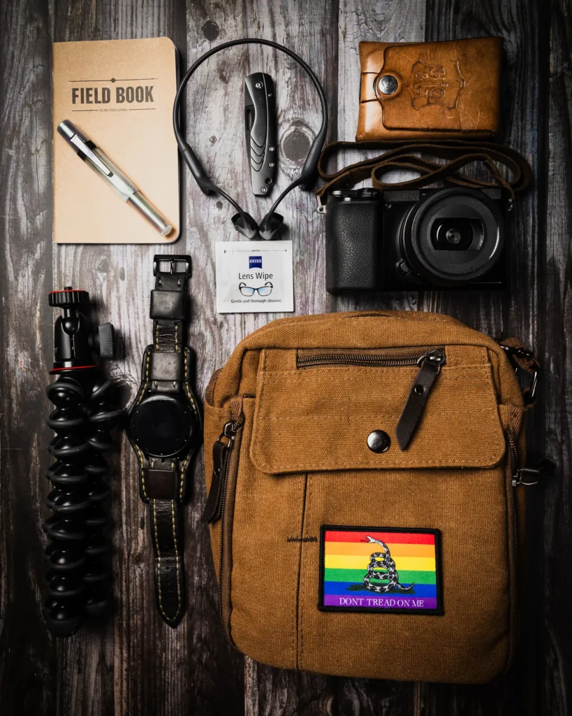 Styled flat lay of a camera bag, photography gear, notebook, and creative tools
