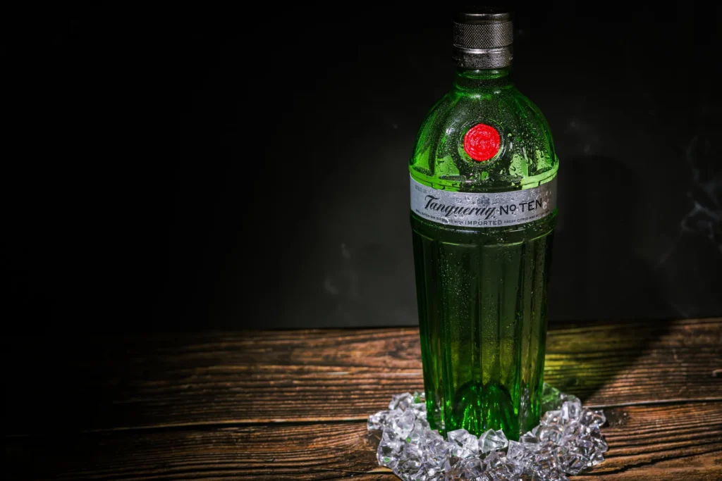 Dramatic product photo of a green glass bottle on a dark wooden surface