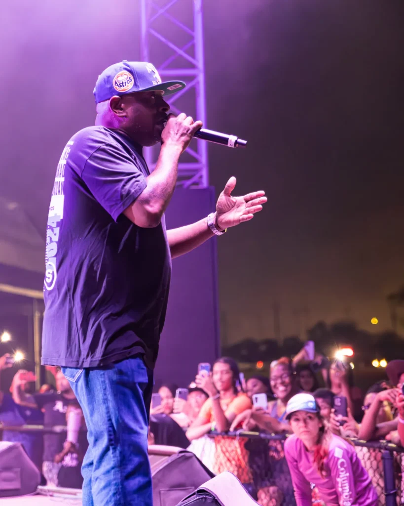 Live event photo of a performer engaging the crowd from an outdoor stage