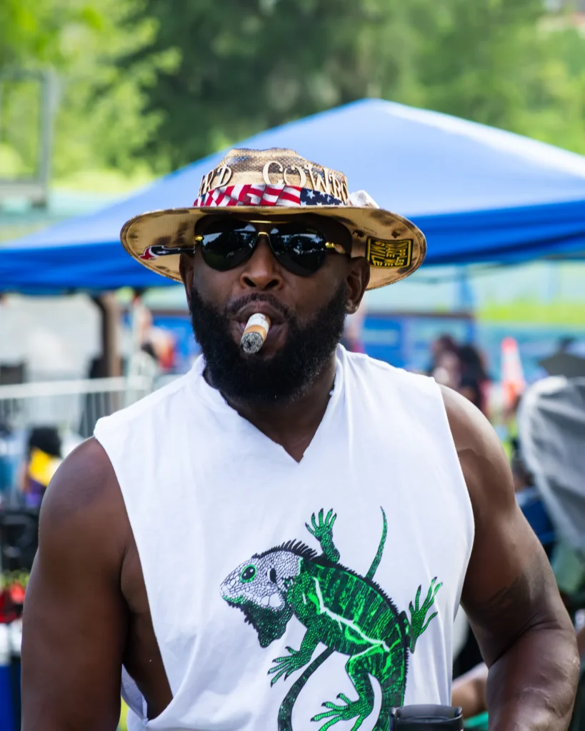 Candid portrait of a man wearing sunglasses and a hat at a community event