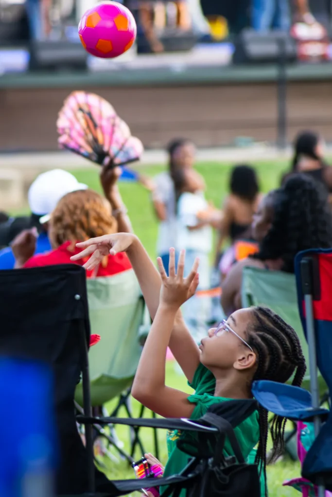 Candid event photo of a child reaching up after tossing a colorful ball