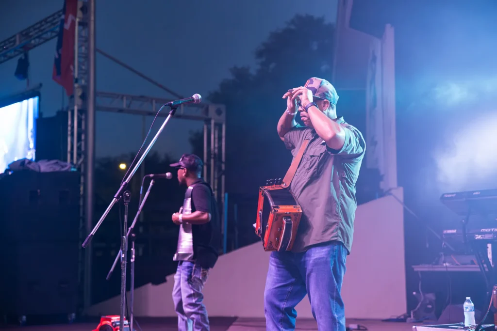 Outdoor concert photo of musicians performing on stage under blue evening light