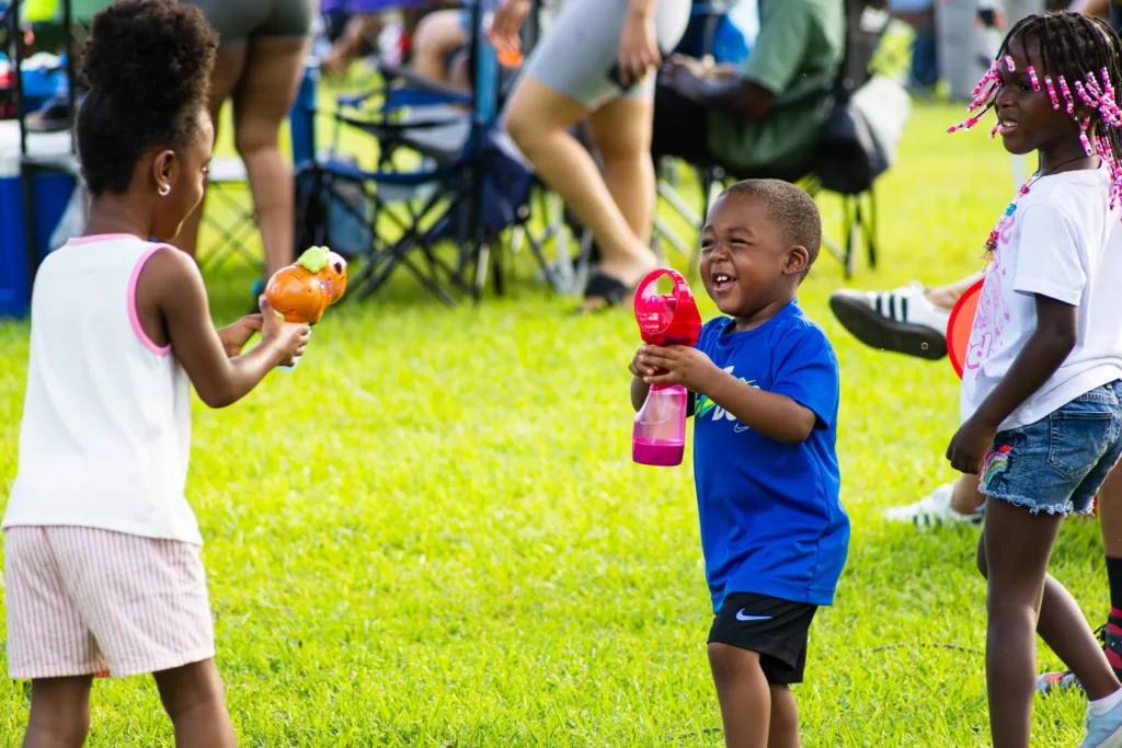 Documentary-style event photography of children playing with bubble toys at an outdoor community celebration