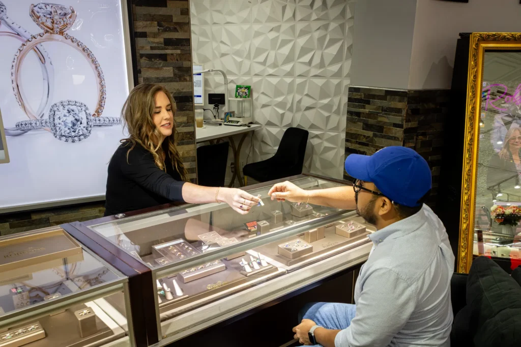 Jewelry store staff member assisting a customer across a display case