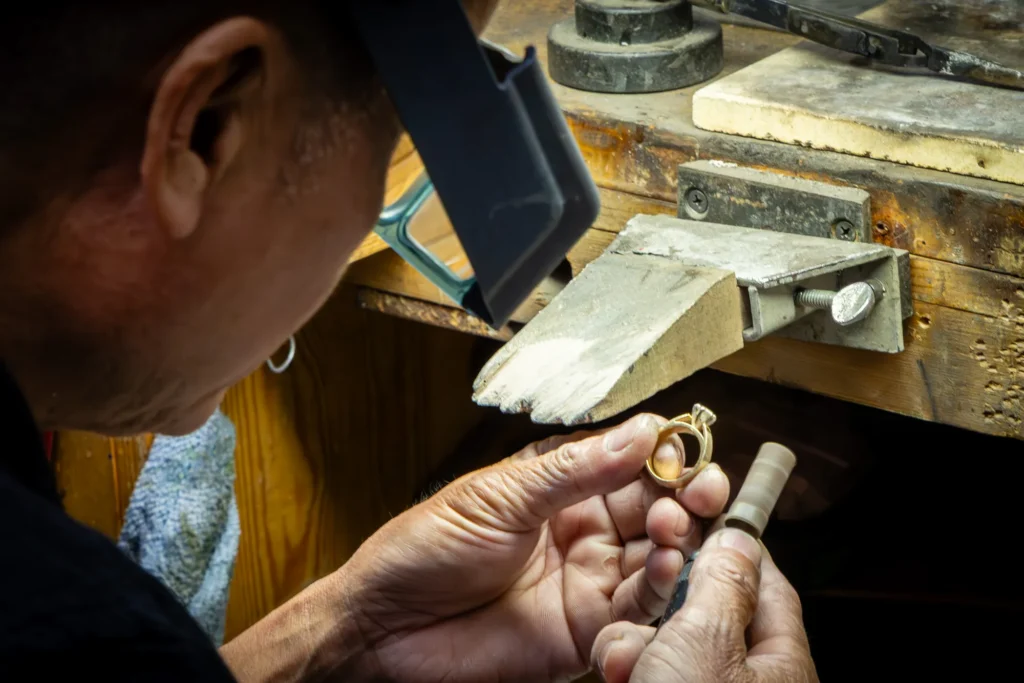 Close-up documentary photo of a jeweler working by hand at a repair bench