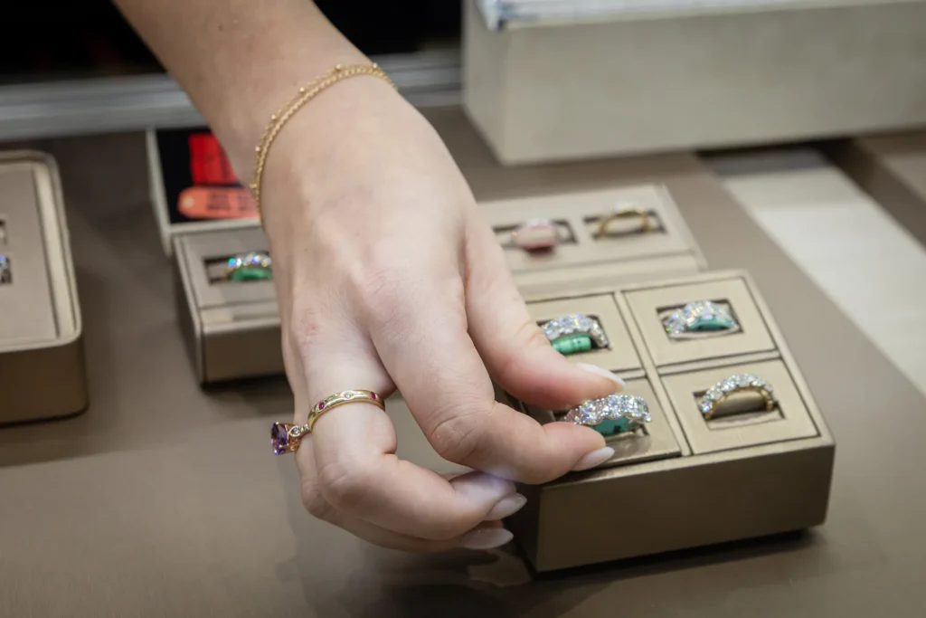 Close-up photo of a hand selecting a ring from a jewelry display tray